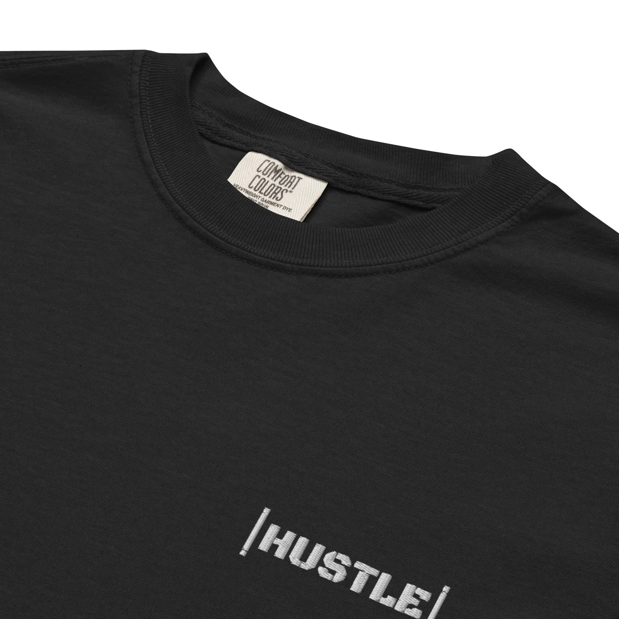 Black oversized streetwear t-shirt with 'HUSTLE' text on a black background zoomed in