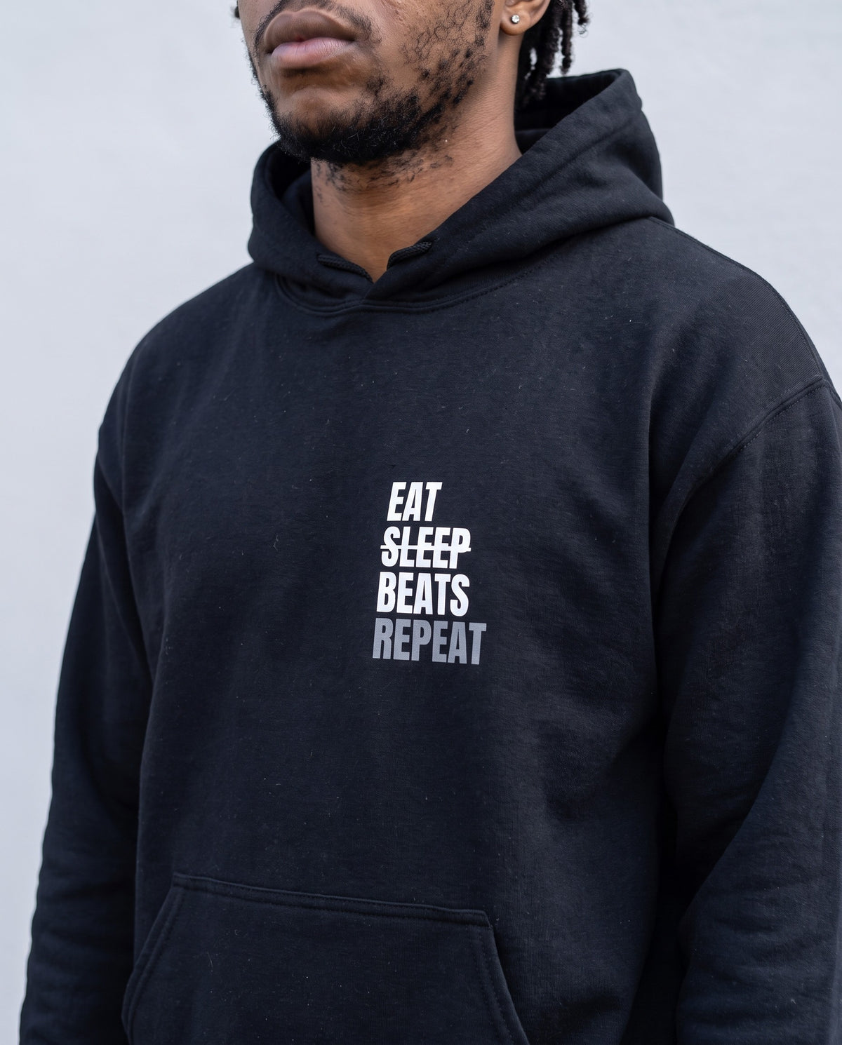 Model wearing the Eat Sleep Beats Repeat hoodie in Black, print close-up