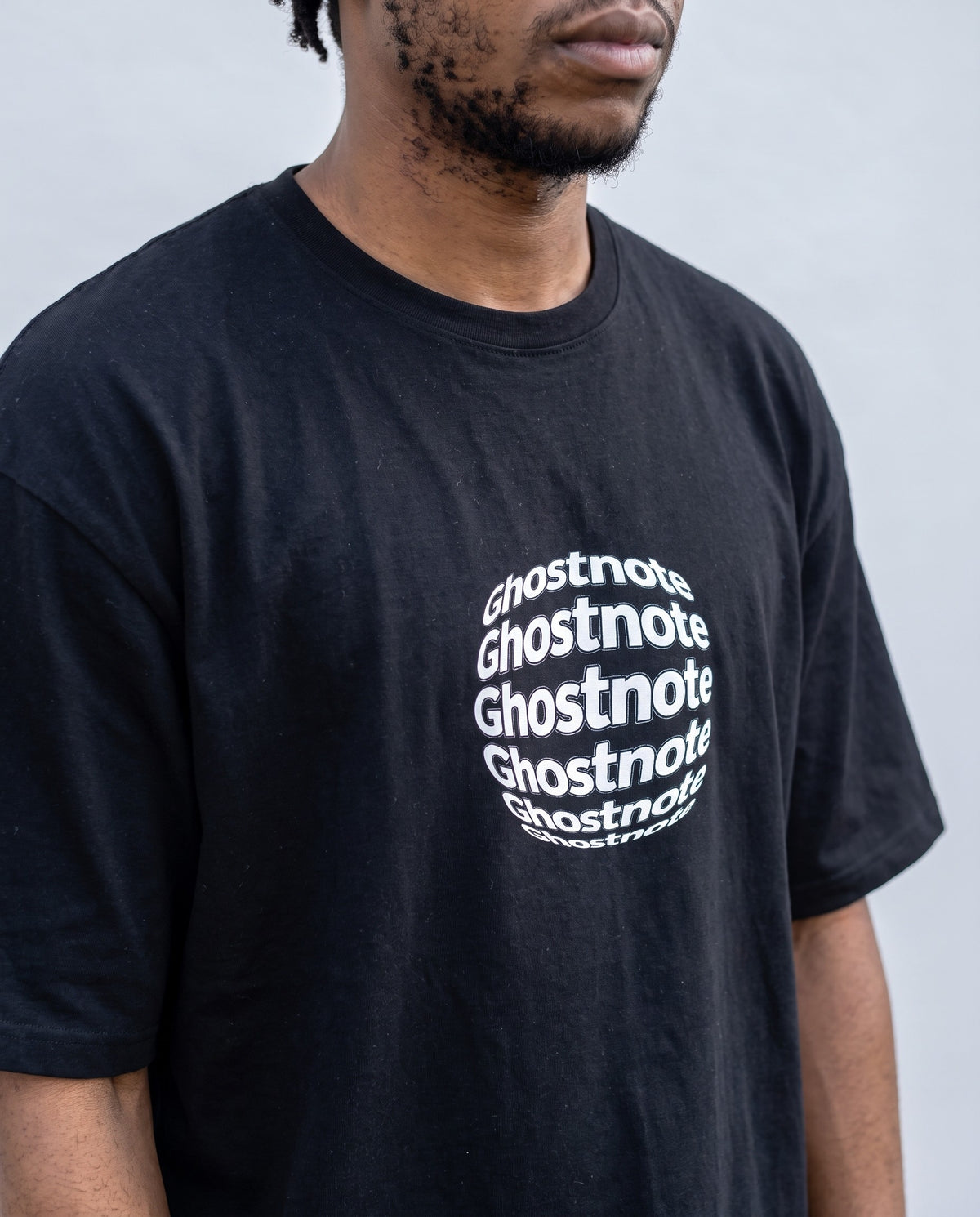 Model wearing the Ghostnote Premium OVERSIZED T-Shirt in Black, print close-up