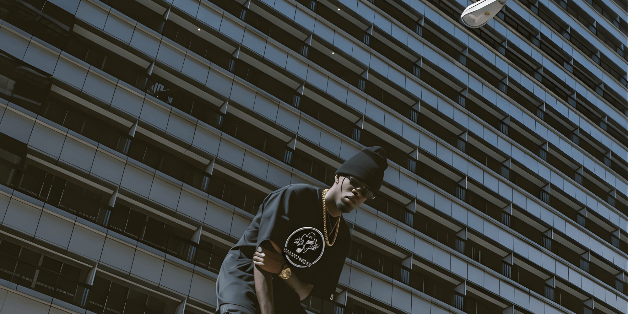 Person standing in front of a tall building with a dark sky wearing a Ghostnote tshirt