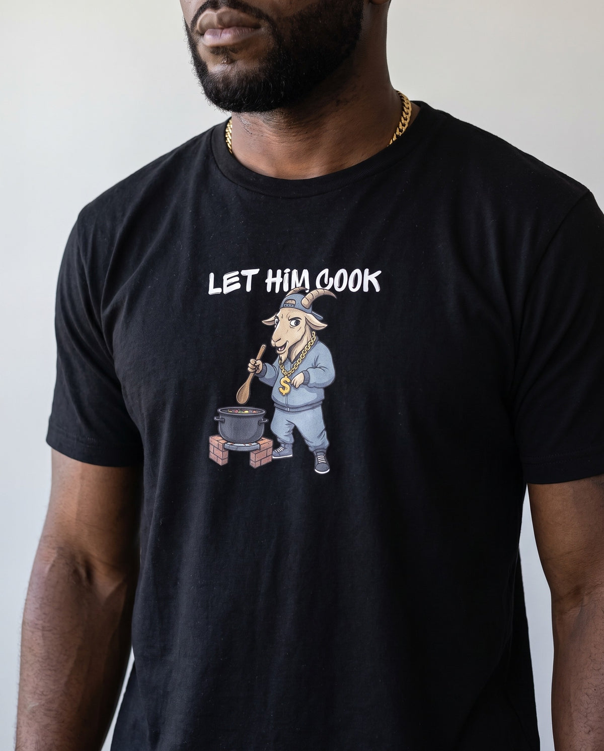 Model wearing the Let Him Cook t-shirt in Black, print close-up