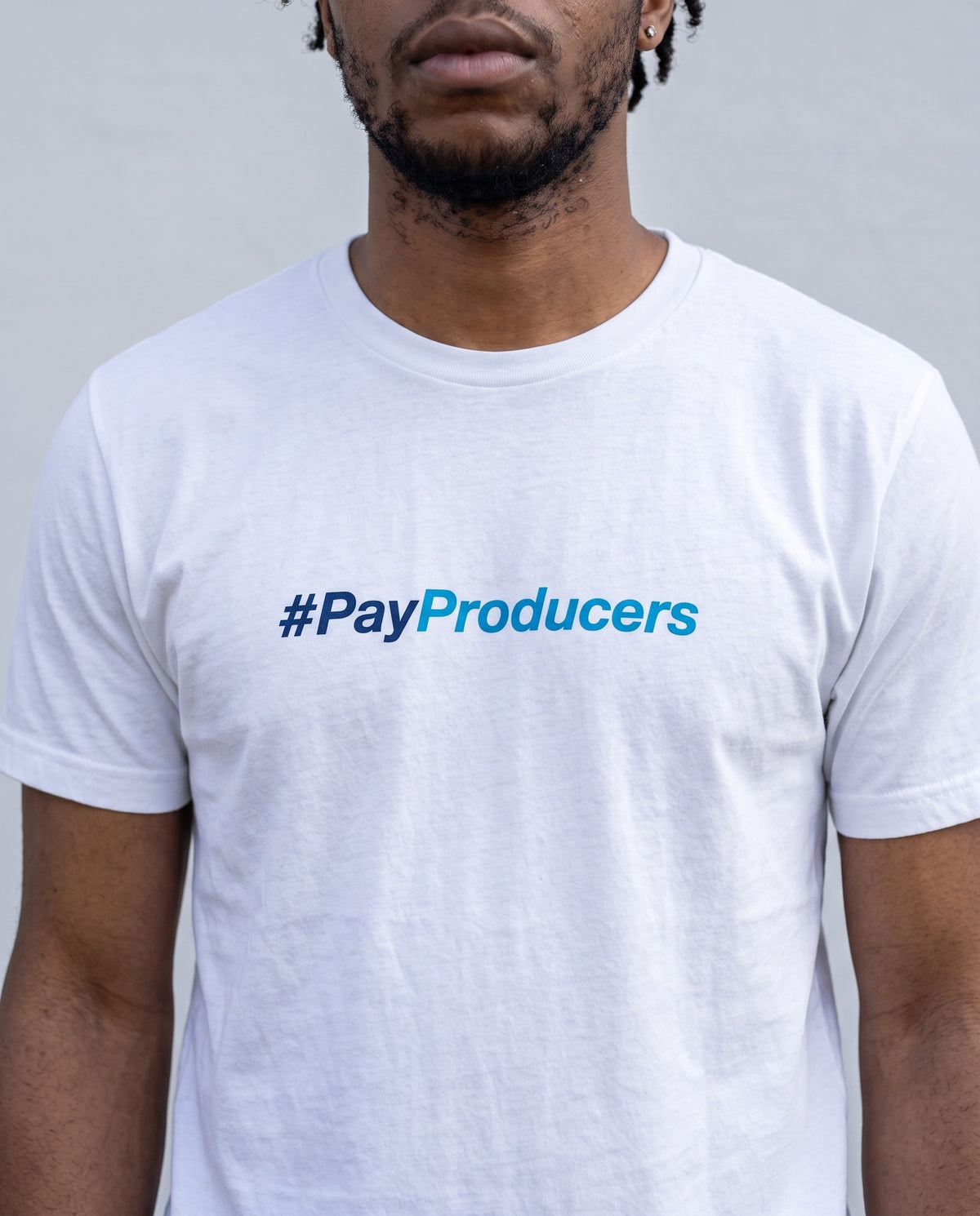 Model wearing the Pay Producer t-shirt in White, print close-up