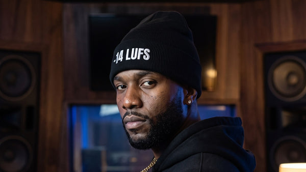 Man wearing the black -14 LUFS beanie in a recording studio control room