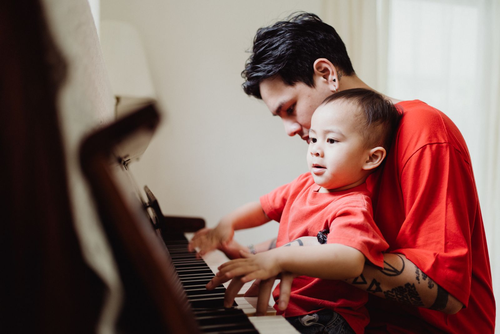 Father teaching his toddler son piano at home — Father's Day gifts for music producer dads