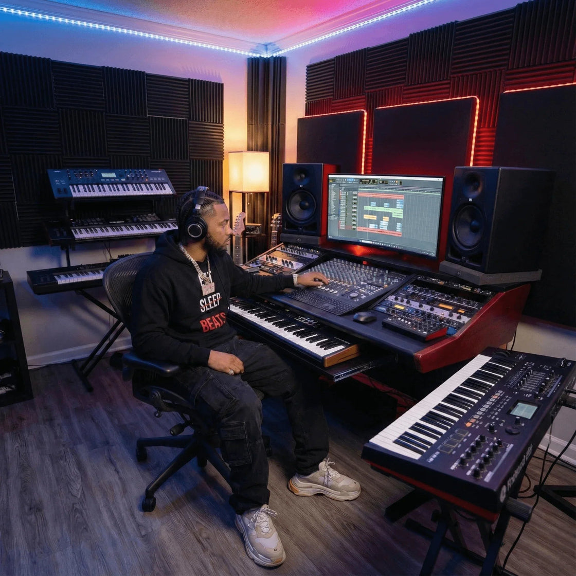 Producer in a black Eat Sleep Beats hoodie at the desk during a late studio session