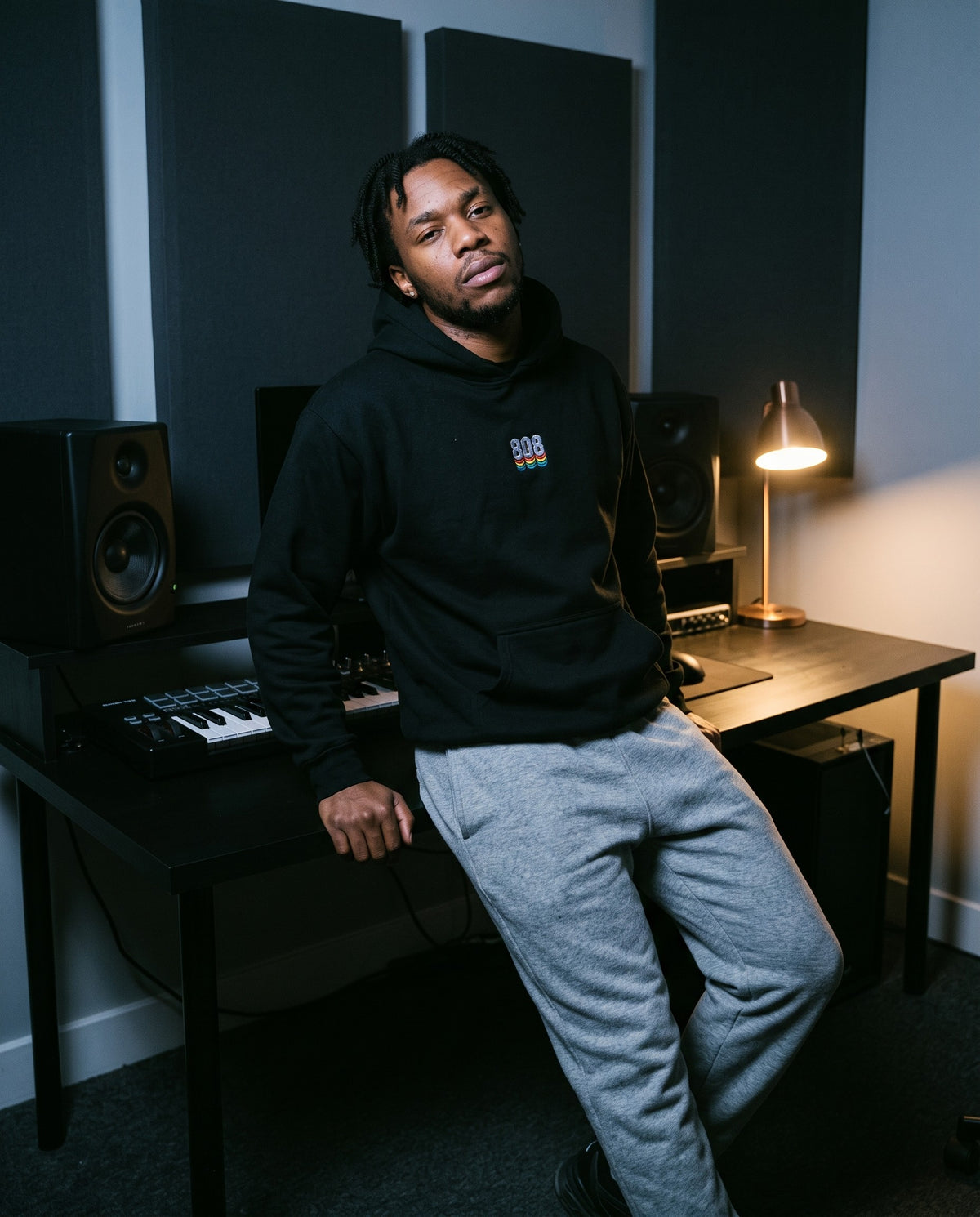 Model wearing the 808 hoodie in Black, in a home studio