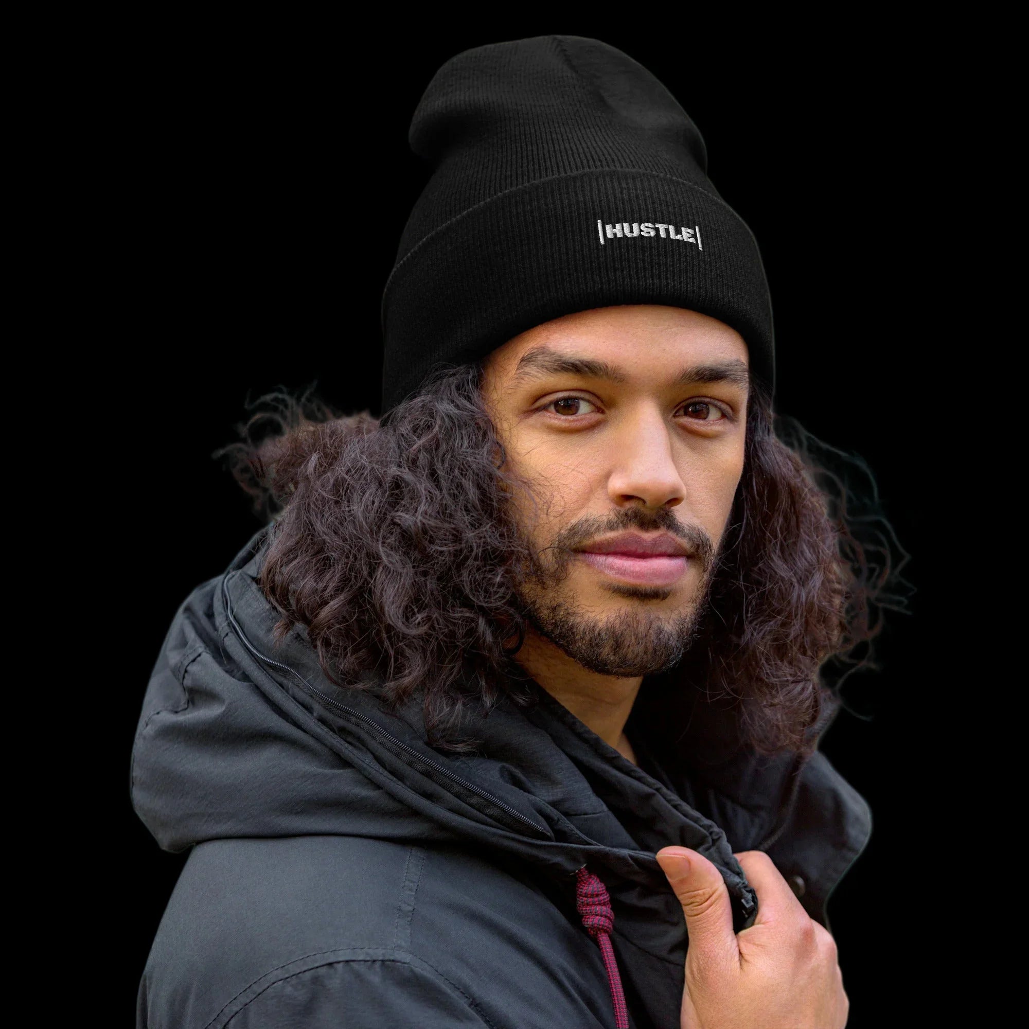 Man wearing a black beanie with 'HUSTLE' text on a teal background