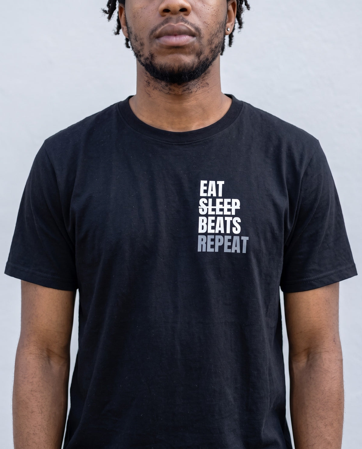 Model wearing the Eat Sleep Beats Repeat t-shirt in Black, print close-up