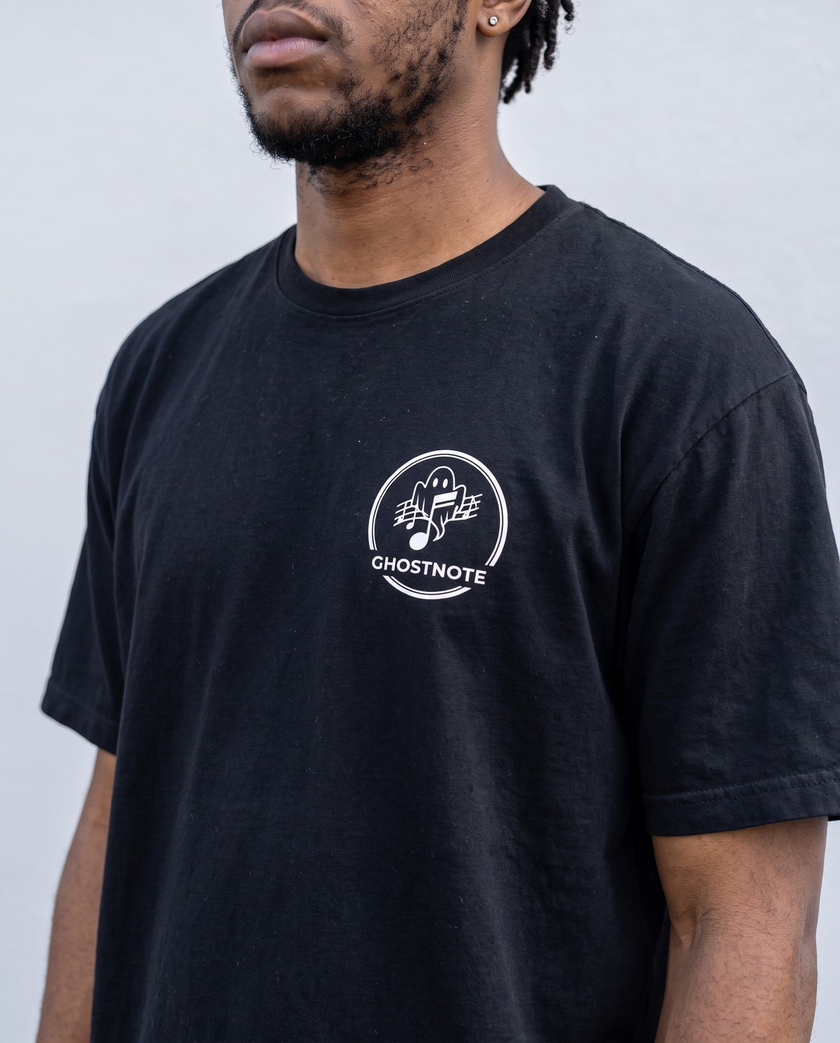 Model wearing the Ghostnote Premium Heavyweight Tee (Dark Colors) in Black, print close-up