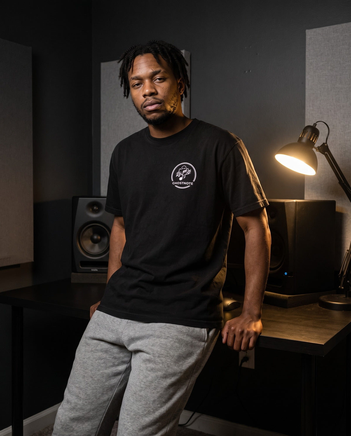Model wearing the Ghostnote Premium Heavyweight Tee (Dark Colors) in Black, in a home studio