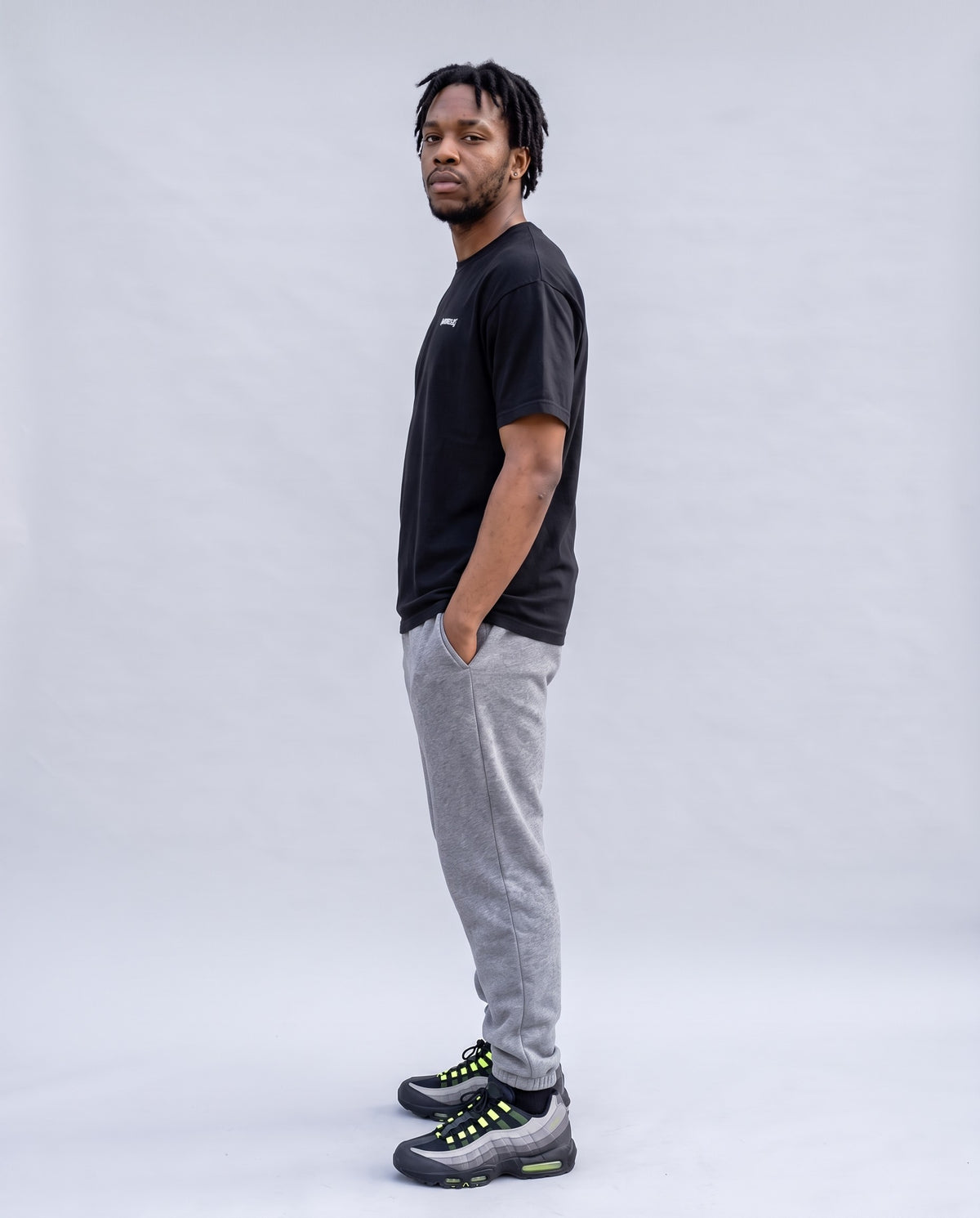 Model wearing the Hustle t-shirt in Black, side profile