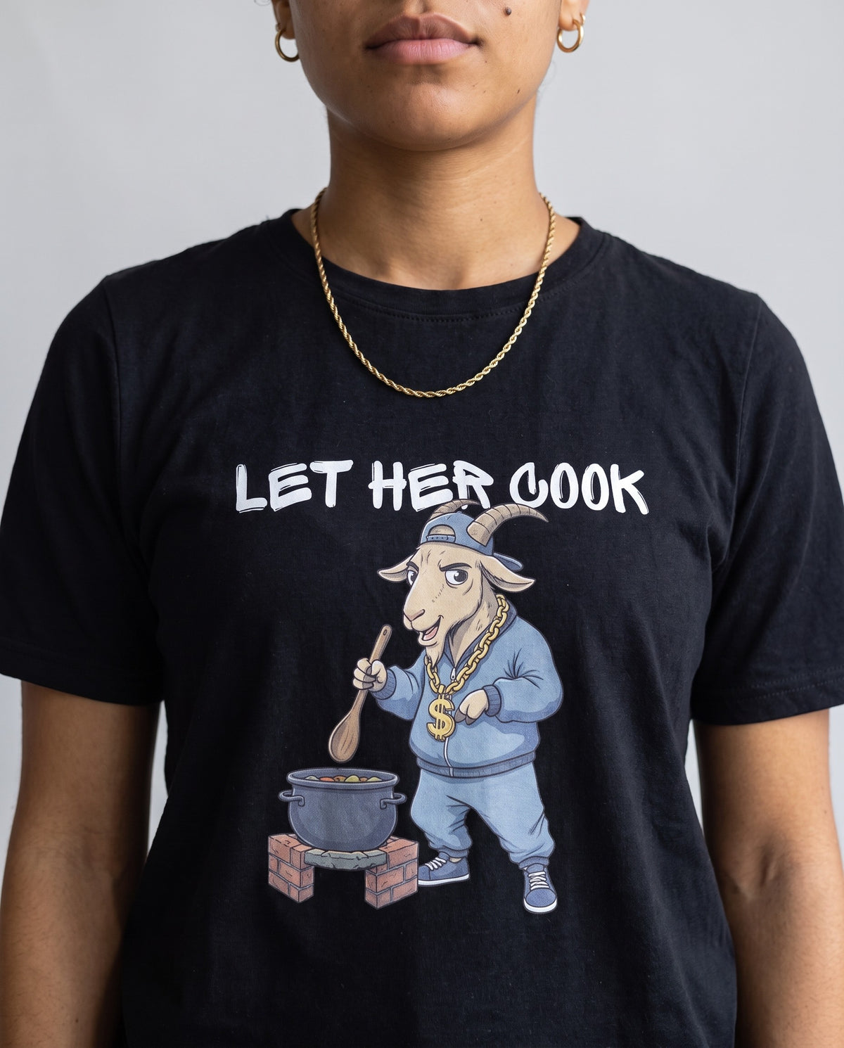 Model wearing the Let Her Cook t-shirt in Black, print close-up