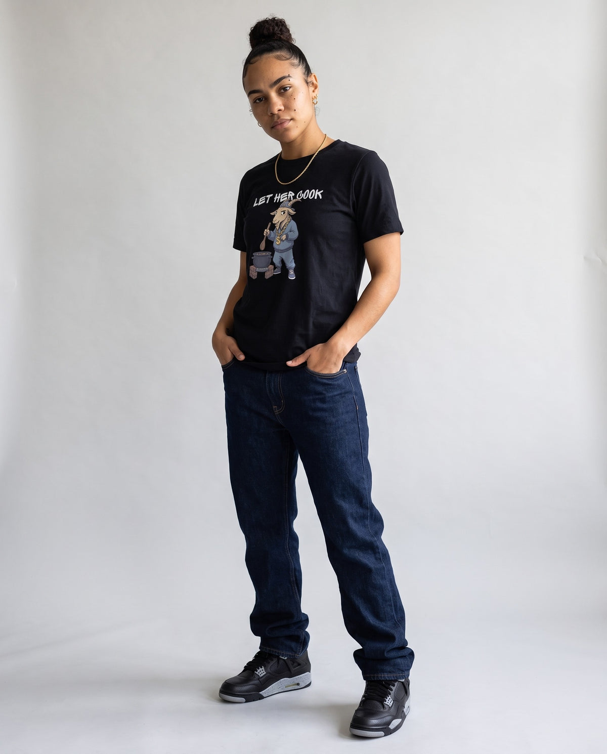 Model wearing the Let Her Cook t-shirt in Black, full length