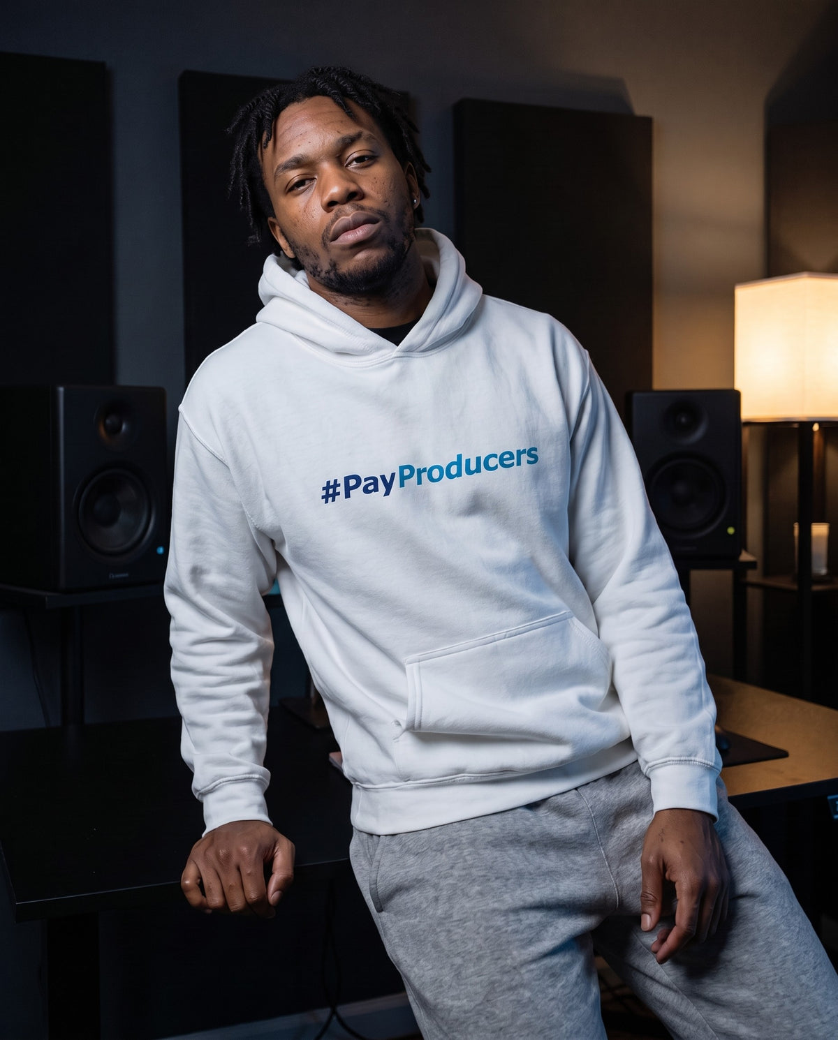 Model wearing the Pay Producer hoodie in White, in a home studio