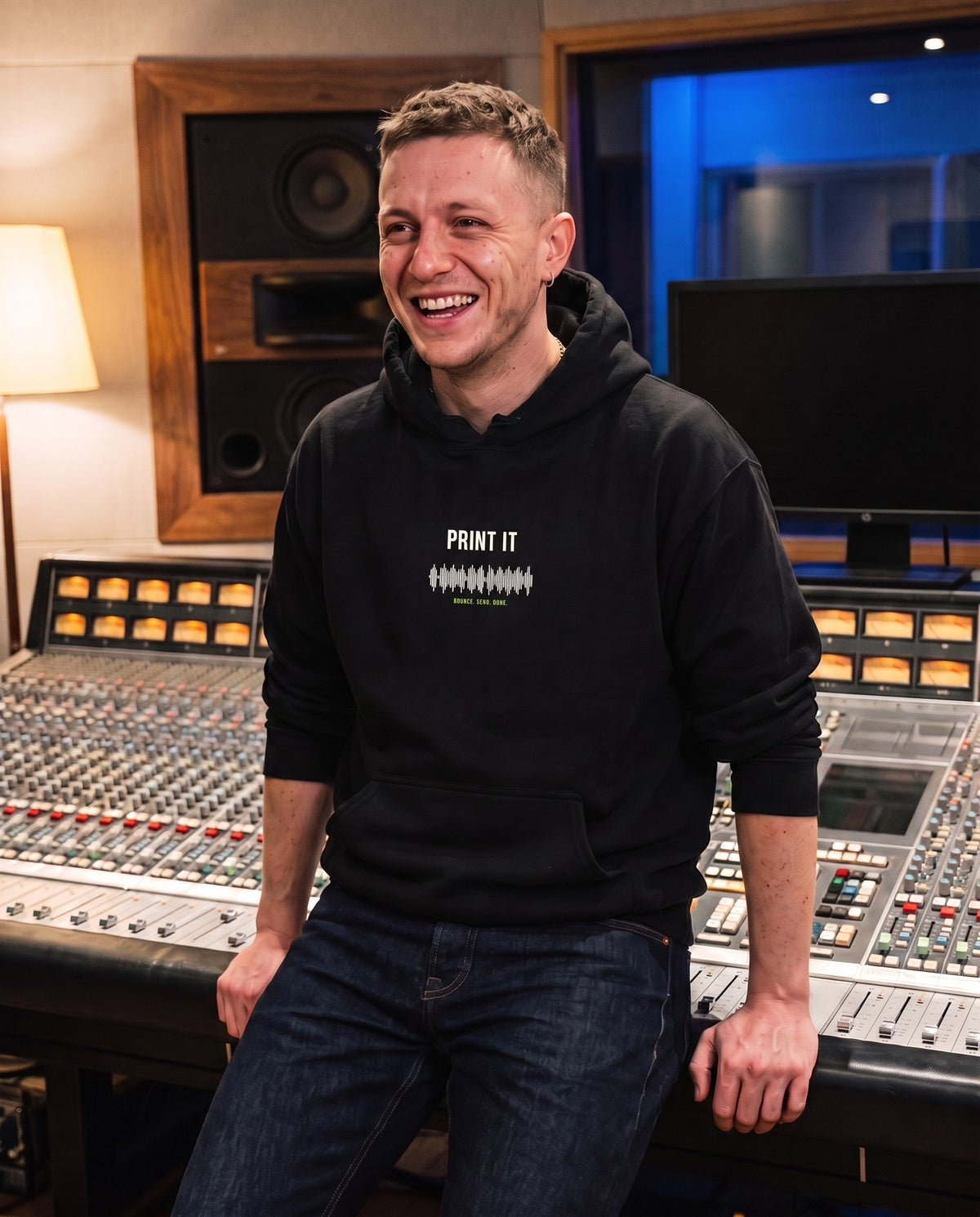 Model wearing the Print It hoodie in Black, in a recording studio control room