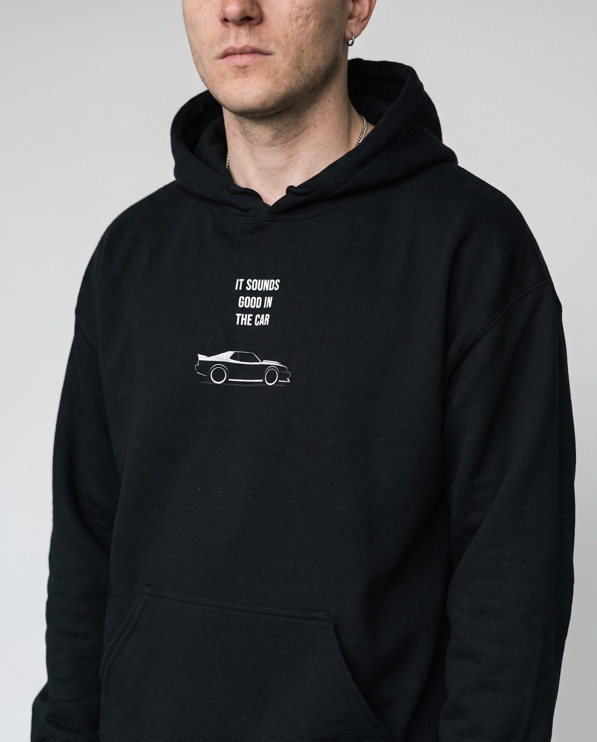 Model wearing the Sounds Good In The Car hoodie in Black, print close-up