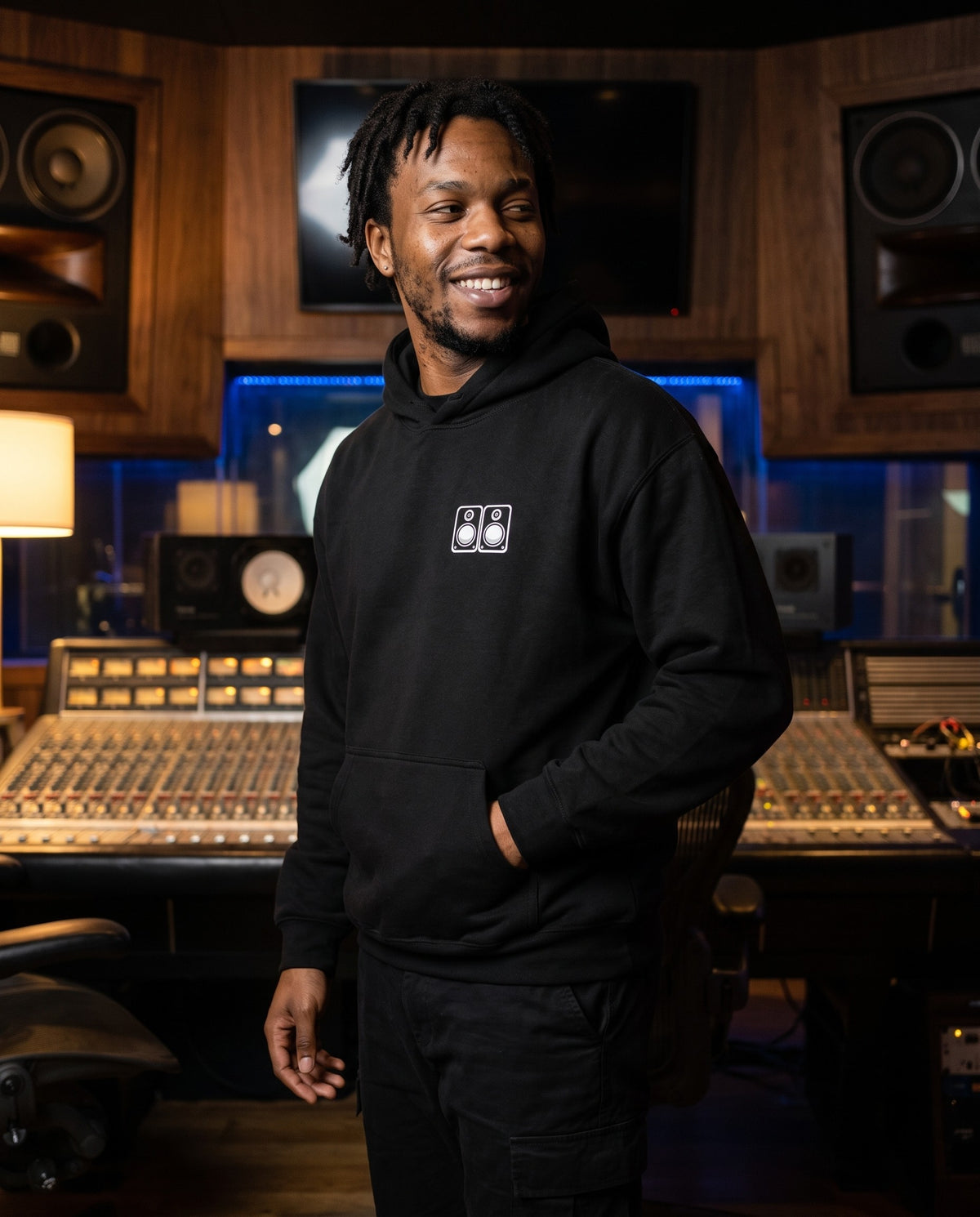 Model wearing the Studio Monitors hoodie in Black, in a recording studio control room